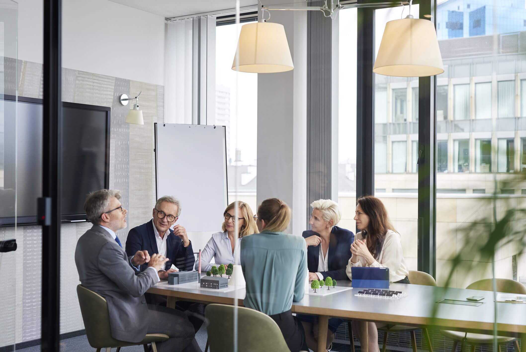 A team of professionals engaged in a meeting around a table in a modern office.