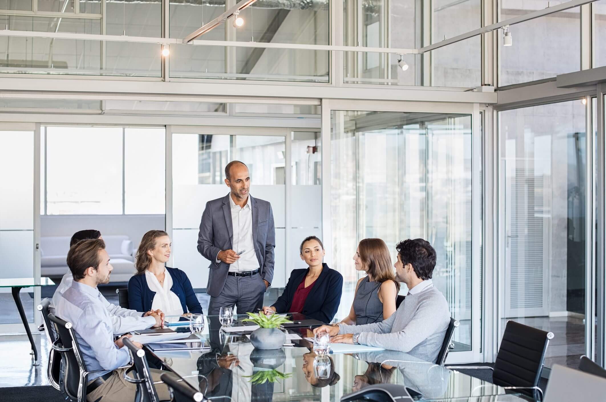 Businessman presenting to colleagues in a modern office meeting.