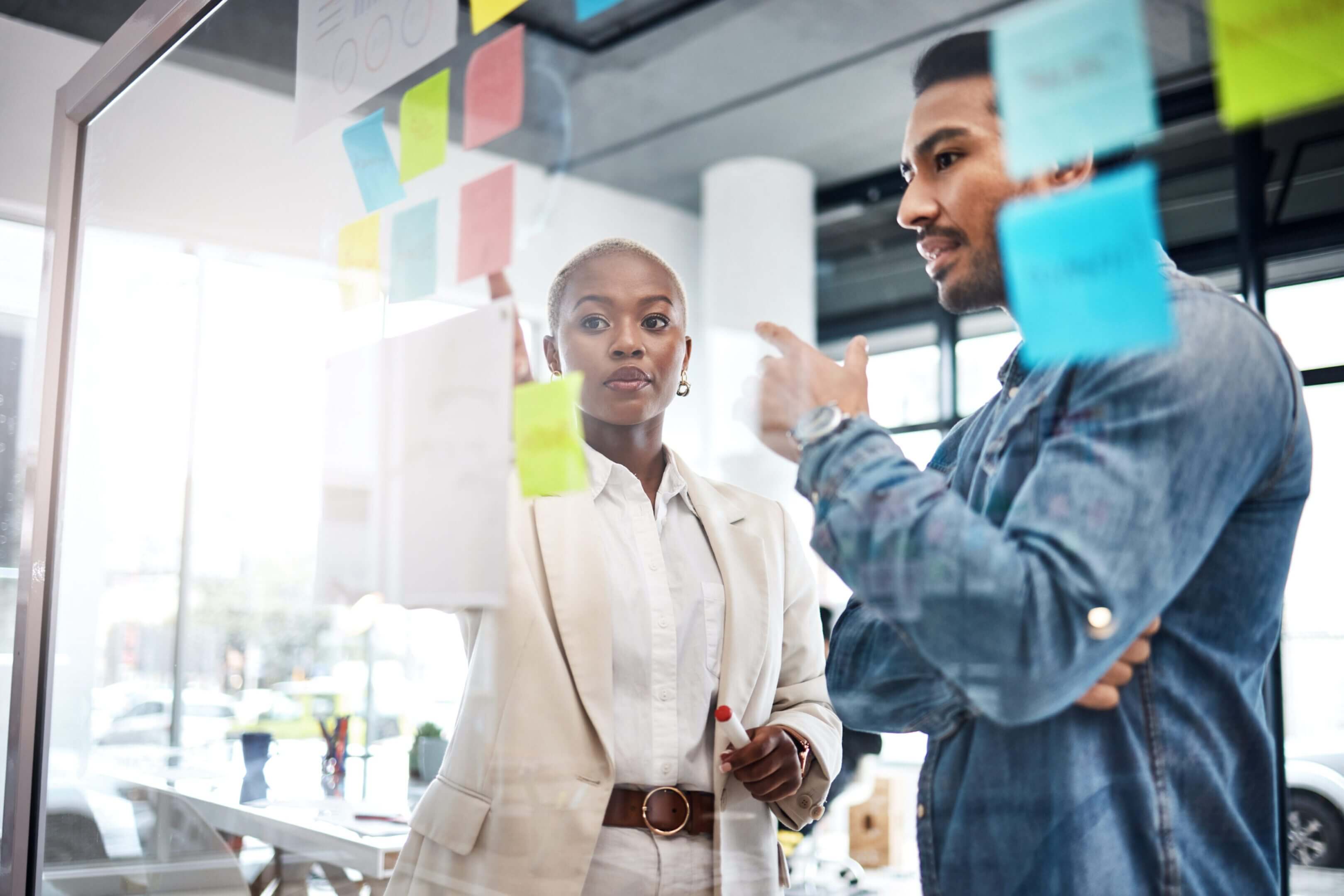 Two professionals discussing ideas with sticky notes in an office.