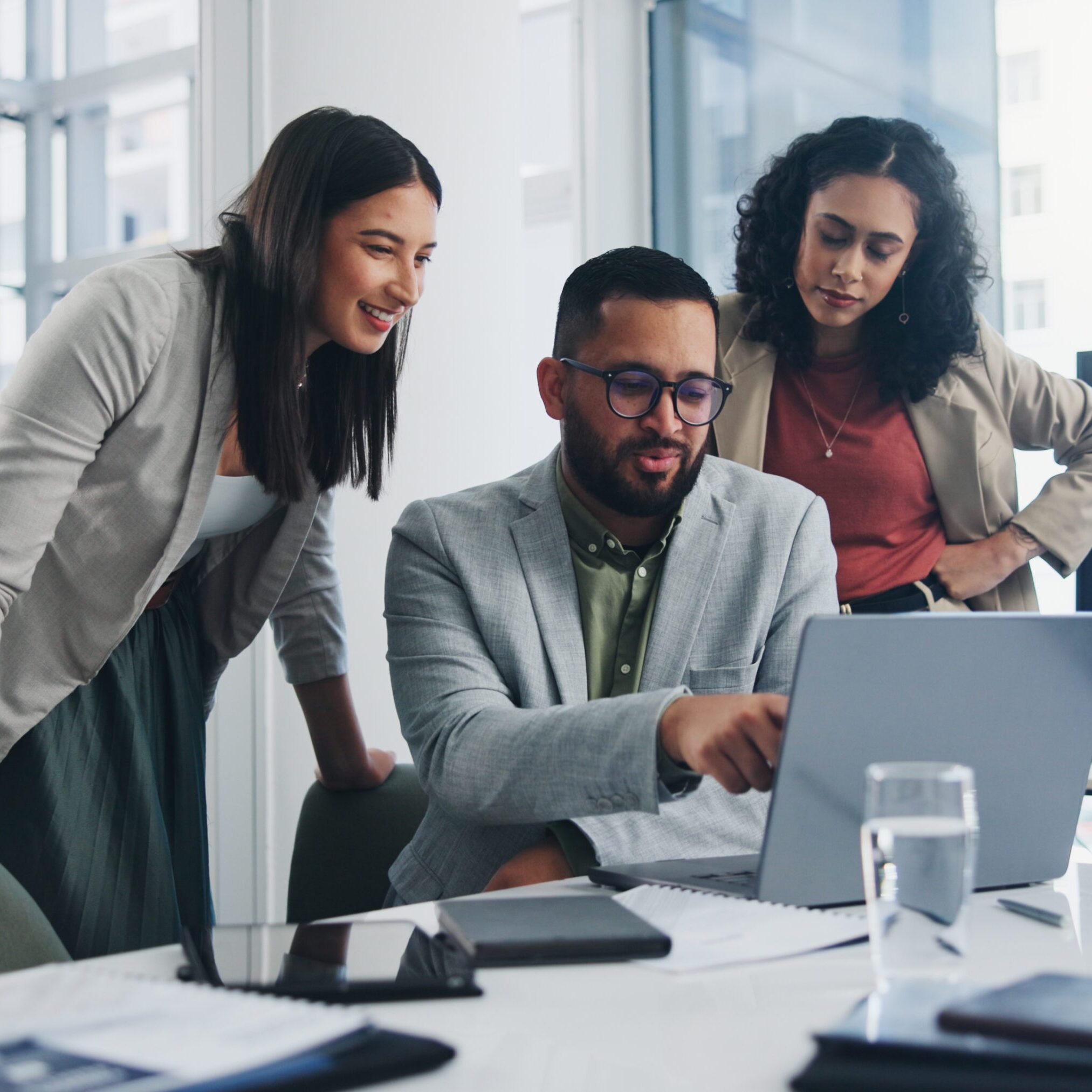 Three professionals collaborating over a laptop in an office.